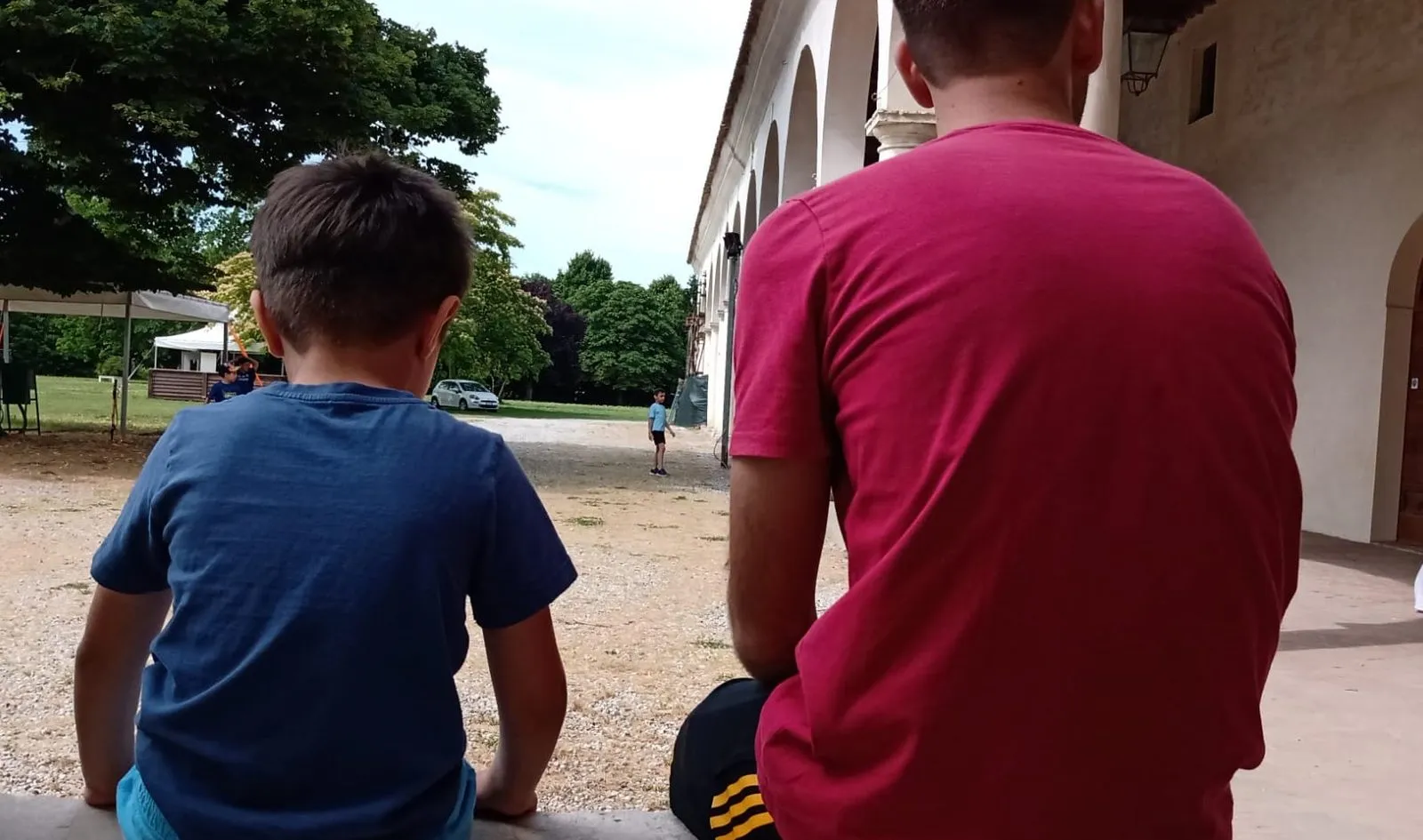 Un adulto e un bambino seduti di spalle, all’aperto