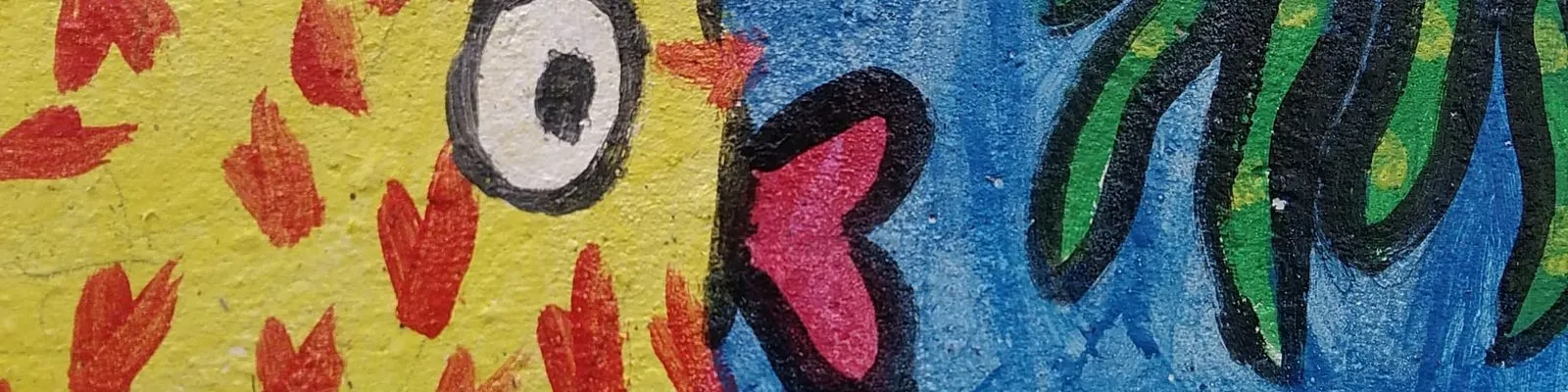 Particolare di un murale dipinto dai bambini: un pesce giallo a macchie rosse tra le alghe